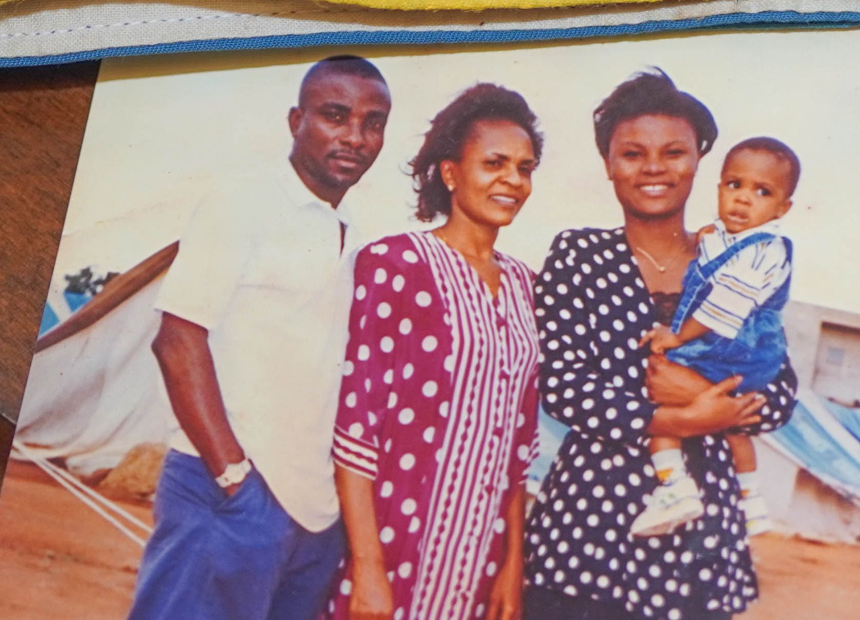 A picture of people dressed nicely in front of tents in a refugee camp