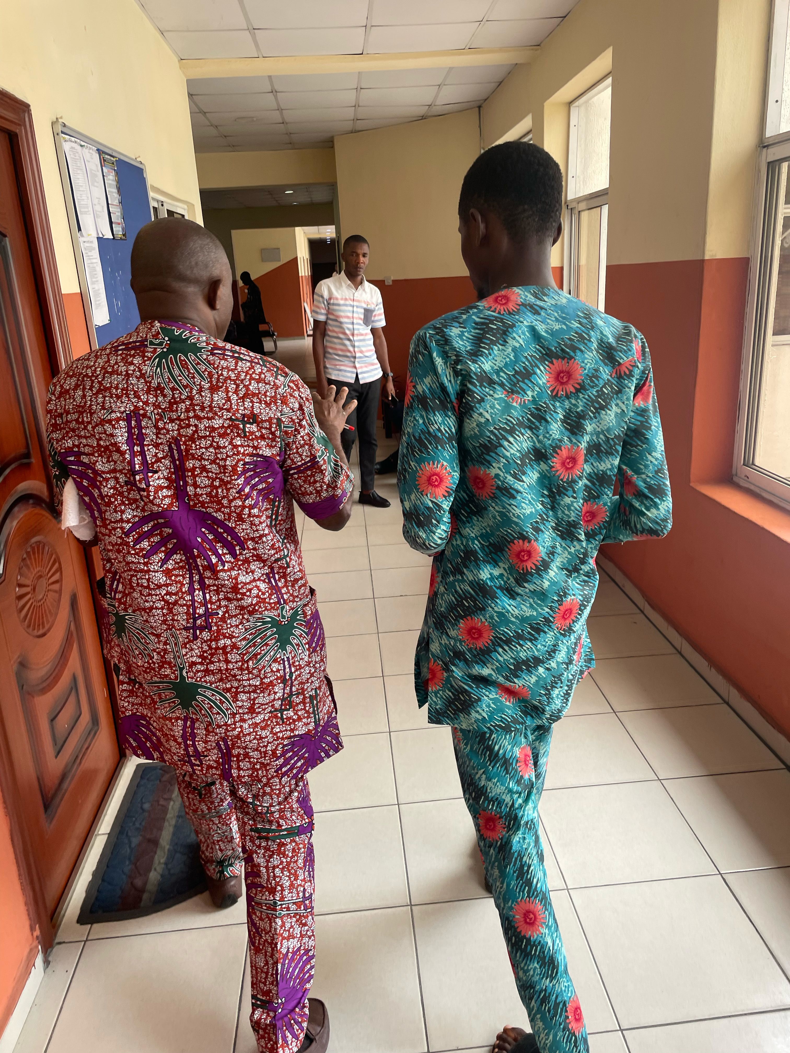 Two people in colorful floral sets walk down the hall and chat with each other